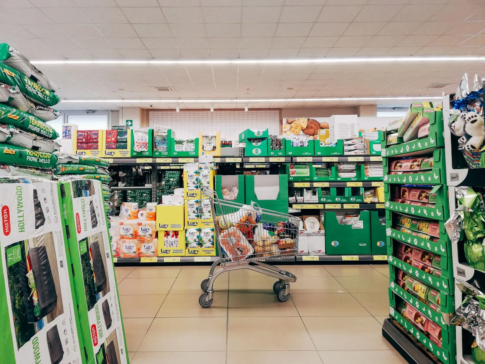 Shopping cart in a supermarket aisle full of competing products