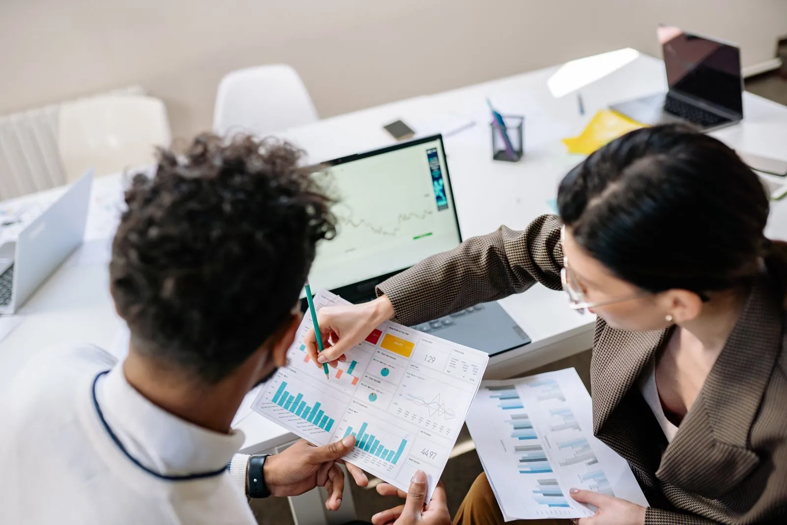 Two colleagues reviewing charts in a printed industry report