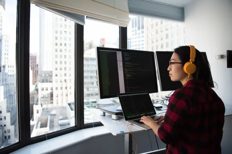 Programistka pracuje przy monitorach z kodem w biurze